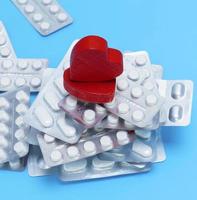 stack of different pills in a package and two red hearts photo