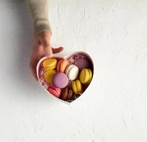 open cardboard box with a baked dessert multi-colored round macarons photo