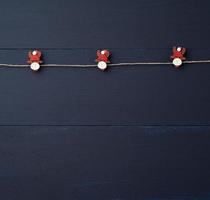 decorative holiday clothespins with a figure of a deer hang on a brown rope photo