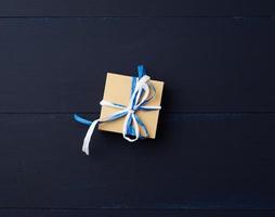 caja cuadrada de regalo de cartón marrón sobre un fondo de madera azul foto