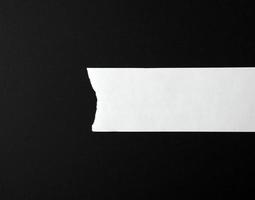 white torn blank strip of paper on a black background photo