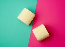 soft yellow toilet paper in a roll on a green-pink background photo