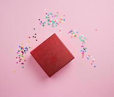 square red shiny box and multicolored sparkles on a pink background photo