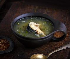 Soup with a piece of mackerel in a brown clay plate photo