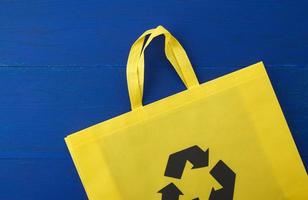 Reusable yellow viscose bag on blue wooden background photo