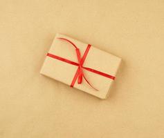 gift wrapped in brown kraft paper and tied with a thin silk ribbon on a background of paper photo