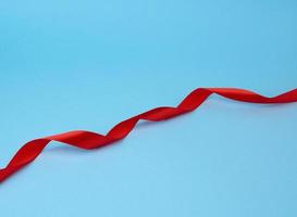 red silk thin ribbon twisted on a blue background photo