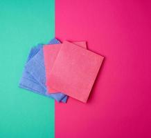 multi-colored square dishwashing sponges on a pink green background photo