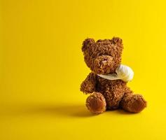 brown teddy bear with a bandaged paw sitting photo