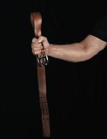 cinturón de cuero marrón con hebilla de hierro en la mano de un hombre foto