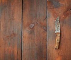 cuchillo afilado de acero vintage sobre una mesa de madera marrón hecha de tablas foto