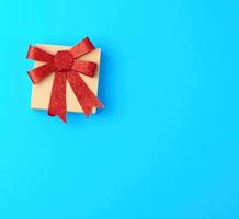 closed brown gift box with a red shiny bow on a blue background photo