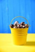 Full bucket of fresh quail eggs in the shell on a yellow surface photo