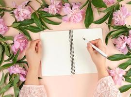 open empty notebook and two female hands, beige background photo