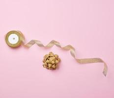 Shiny golden satin ribbon and bow on a pink background photo