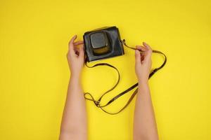 two female hands are holding an old film camera in a brown leather case photo