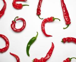 many red whole fruits of hot pepper and one green on a white background photo