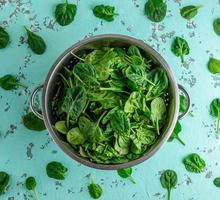 hojas de espinacas verdes en un colador de hierro foto