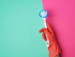 white plastic cleaning brush in hand, protective orange glove on hand photo
