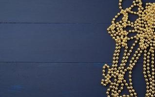 Christmas garland of round golden beads strung on a string, blue wooden background from board photo