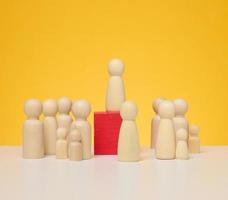 Wooden figurines of men on a yellow background. Public speaking concept, leadership and discussion photo