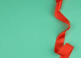 twisted red silk ribbon, green background, top view photo