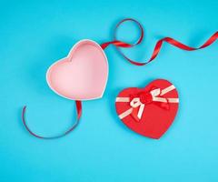 open red heart-shaped gift box with a bow on a blue background photo