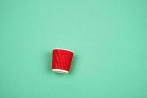 red paper cup with corrugated edges for hot drinks on a green background photo