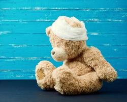 sad brown bear sits with bandaged white medical bandage head photo