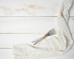 two rope-tied aluminum forks on a white wooden background photo