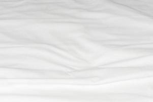 White crumpled or wrinkled bedding sheet or blanket with pattern after guest's use taken in hotel or resort room with copy space. Untidy blanket background texture photo