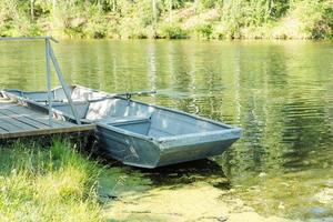 an old boat with oars on a green pond against the backdrop of a forest. photo