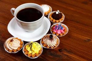 Closeup shot of small cup of coffee with colorful cupcakes photo