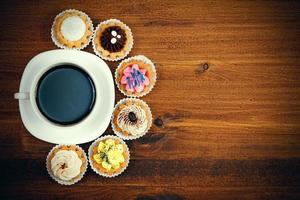 Closeup shot of small cup of coffee with colorful cupcakes. Flat lay style photo