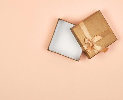 caja de regalo cuadrada dorada abierta con un lazo foto