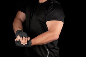 adult athlete in black uniform is standing in a rack with strained muscles photo