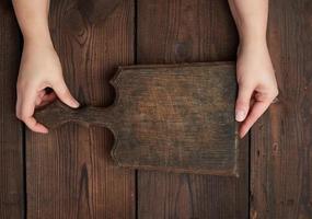 two hands holding a vintage brown empty kitchen cutting board with a handle photo