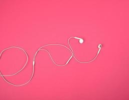 auriculares blancos con un cable sobre un fondo rosa foto