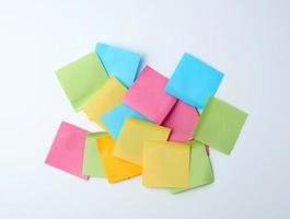 pile of multicolored paper square stickers on white background photo