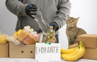 el hombre recoge alimentos, frutas y cosas en una caja de cartón para ayudar a los necesitados y los pobres foto