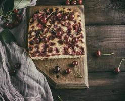 baked cake with cherries on a brown wooden board photo