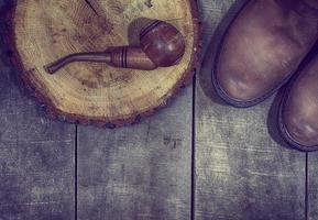 Wooden smoking pipe tobacco with a pair of leather boots photo