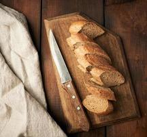 sliced rye flour baguette on a wooden cutting board photo