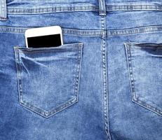 teléfono inteligente en el bolsillo trasero de los jeans azules foto