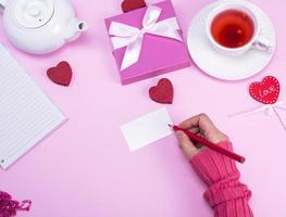 Female hand with a red pencil signs a greeting card photo