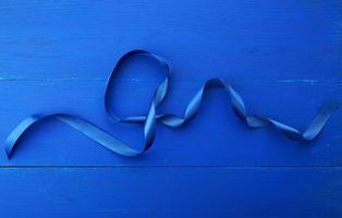 cinta azul de seda retorcida sobre un fondo de madera azul foto