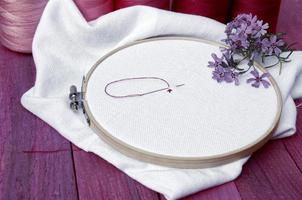 White fabric with red and pink thread for cross stitch photo