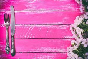 Iron fork and knife on a pink wooden background, empty space in the middle photo