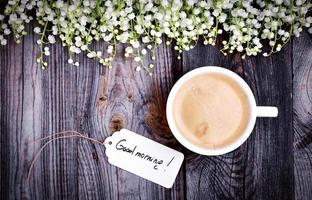 White cup with coffee on a gray wooden surface, top view photo