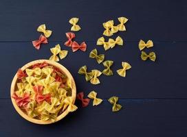 raw pasta in the form of bows in a wooden round plate and white textile napkin photo